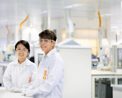 Two scientists in a lab looking at camera smiling