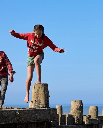 Adult man and 10-year-old girl climb on the pier by the beach in Norfolk.