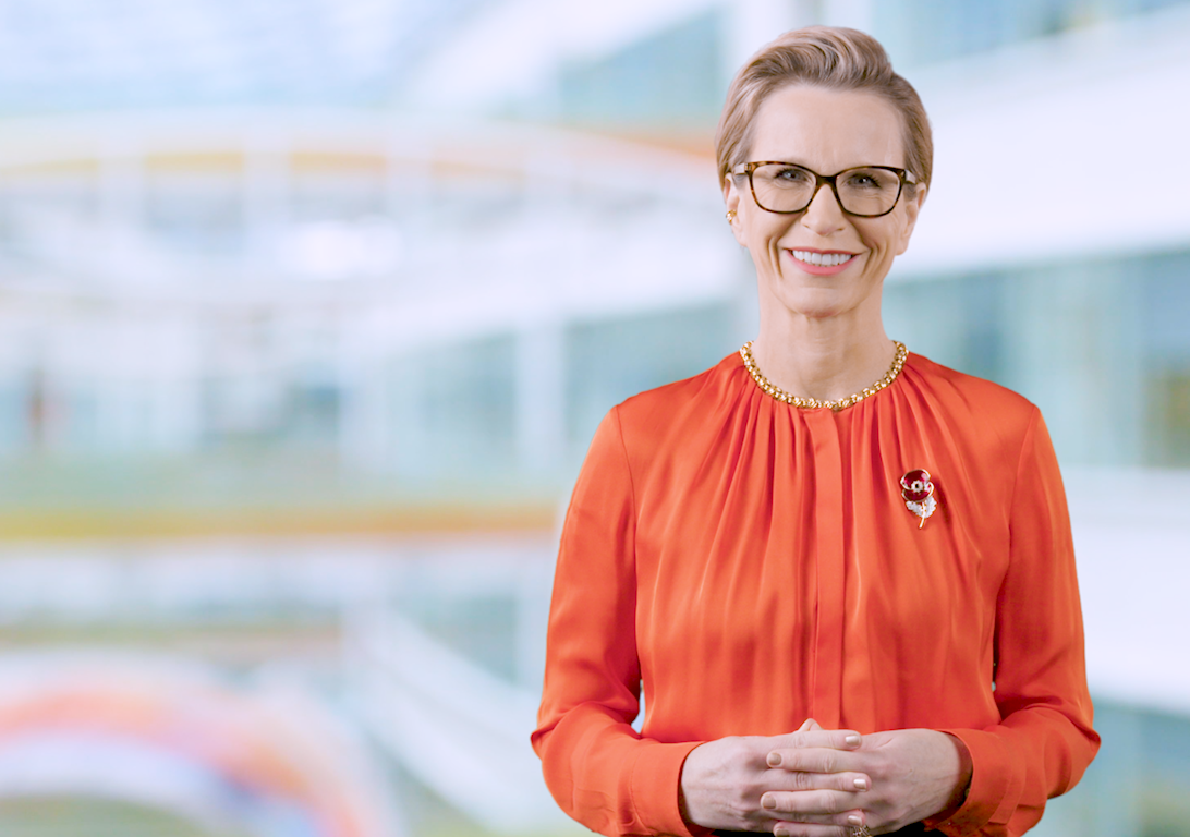 Emma Walmsley, CEO of GSK, wears a orange blouse, glasses and a remembrance poppy and smiles warmly