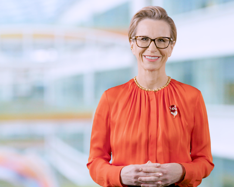 Emma Walmsley, CEO of GSK, wears a orange blouse, glasses and a remembrance poppy and smiles warmly