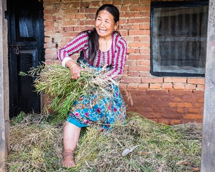Lady smiling holding plants in Nepal