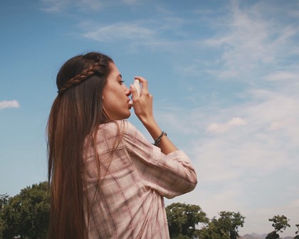 A women outside using an inhaler