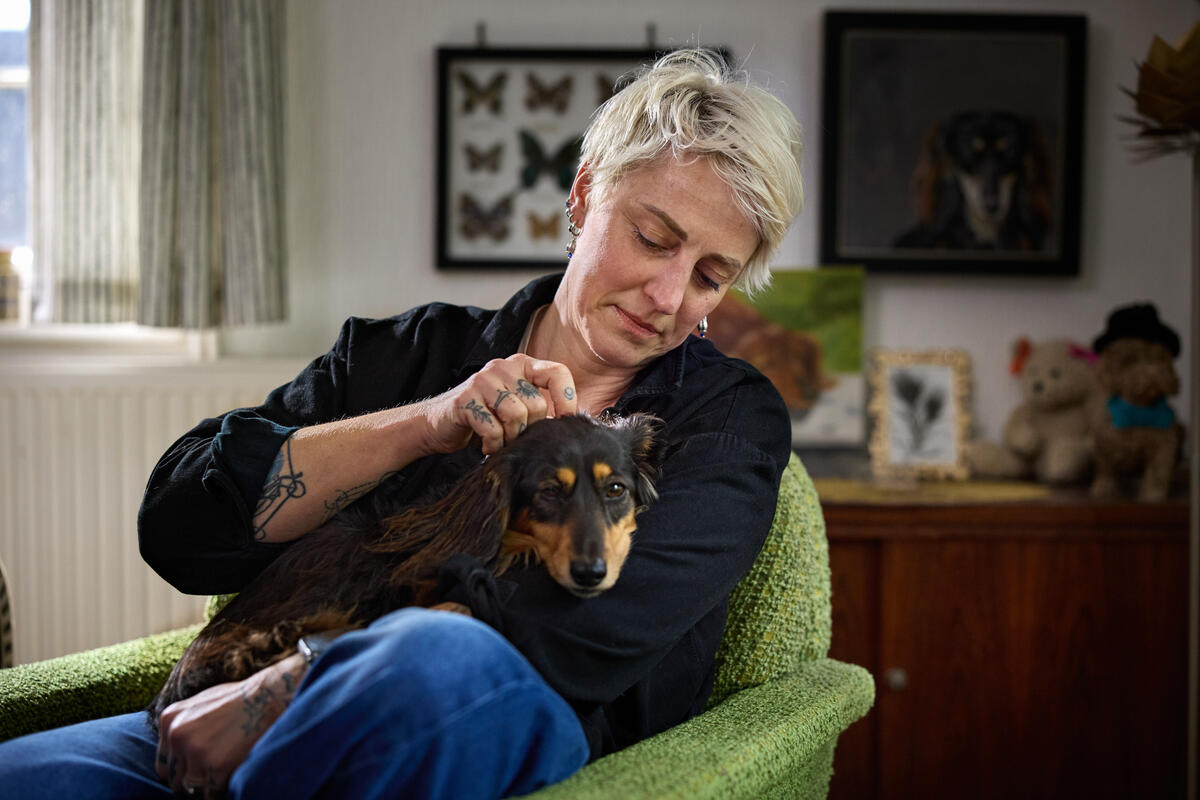 female adult at home with dog sitting on her lap
