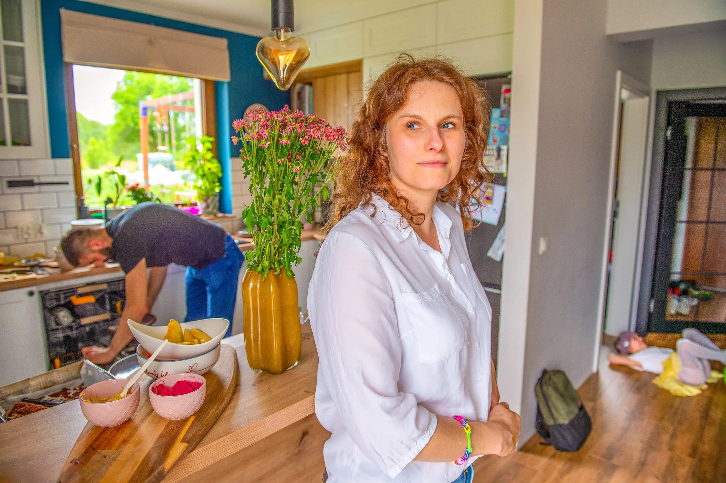 Natalia in the kitchen, her husband and child in the background