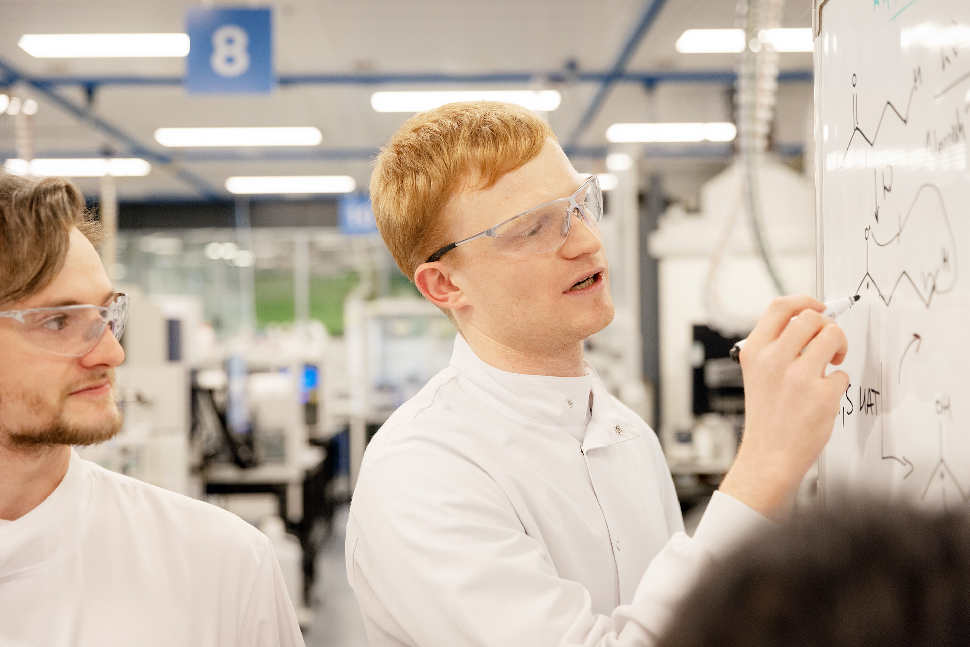 R&D scientist developing and discussing chemistry formulas in smart laboratory.