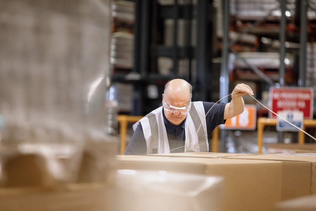 GSK warehouse operative at Ware packing and securing product boxes.