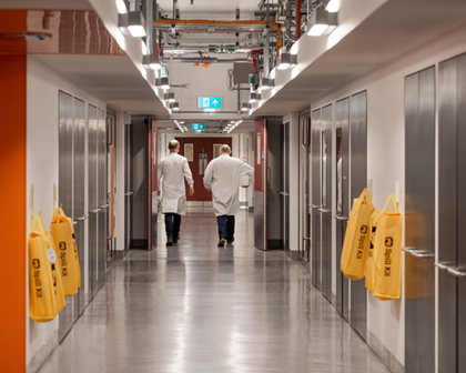 Two men in labcoats walking down long hallway