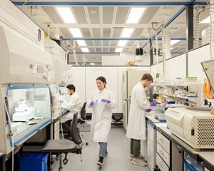 Two men and a woman wearing lab coats in a research lab