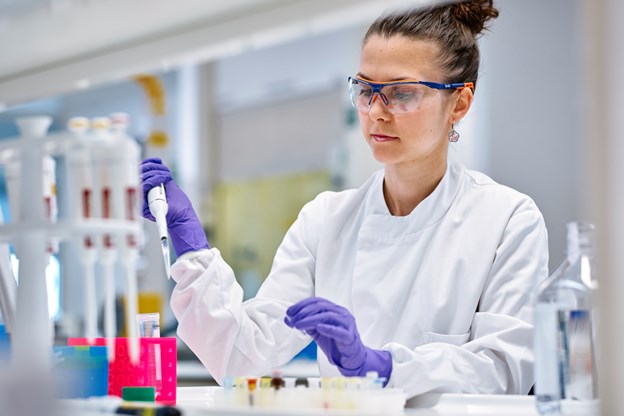 Woman in labcoat using a syringe