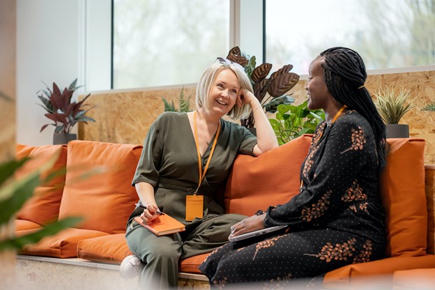 Two women speaking on a couch