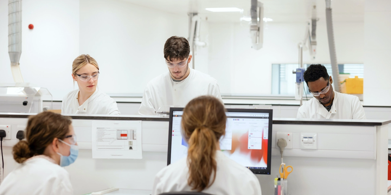 Five lab workers carrying out tasks