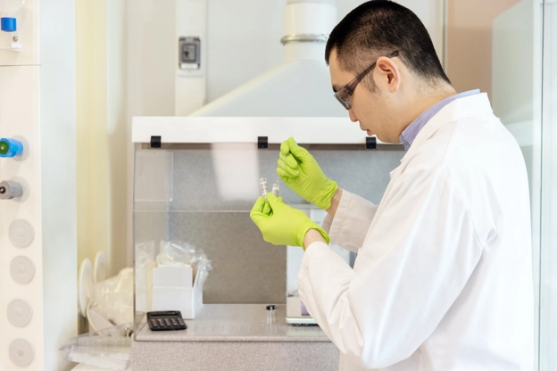 Man in lab coat filling vials