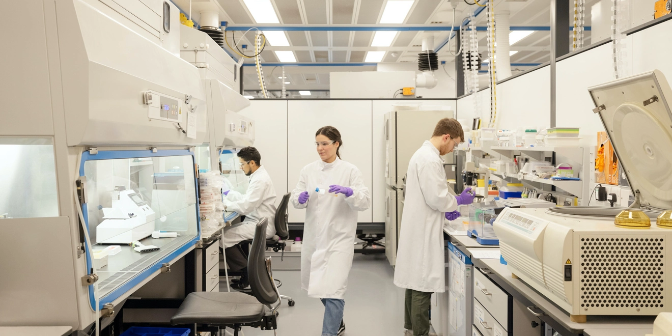 Two men and a woman wearing lab coats in a research lab
