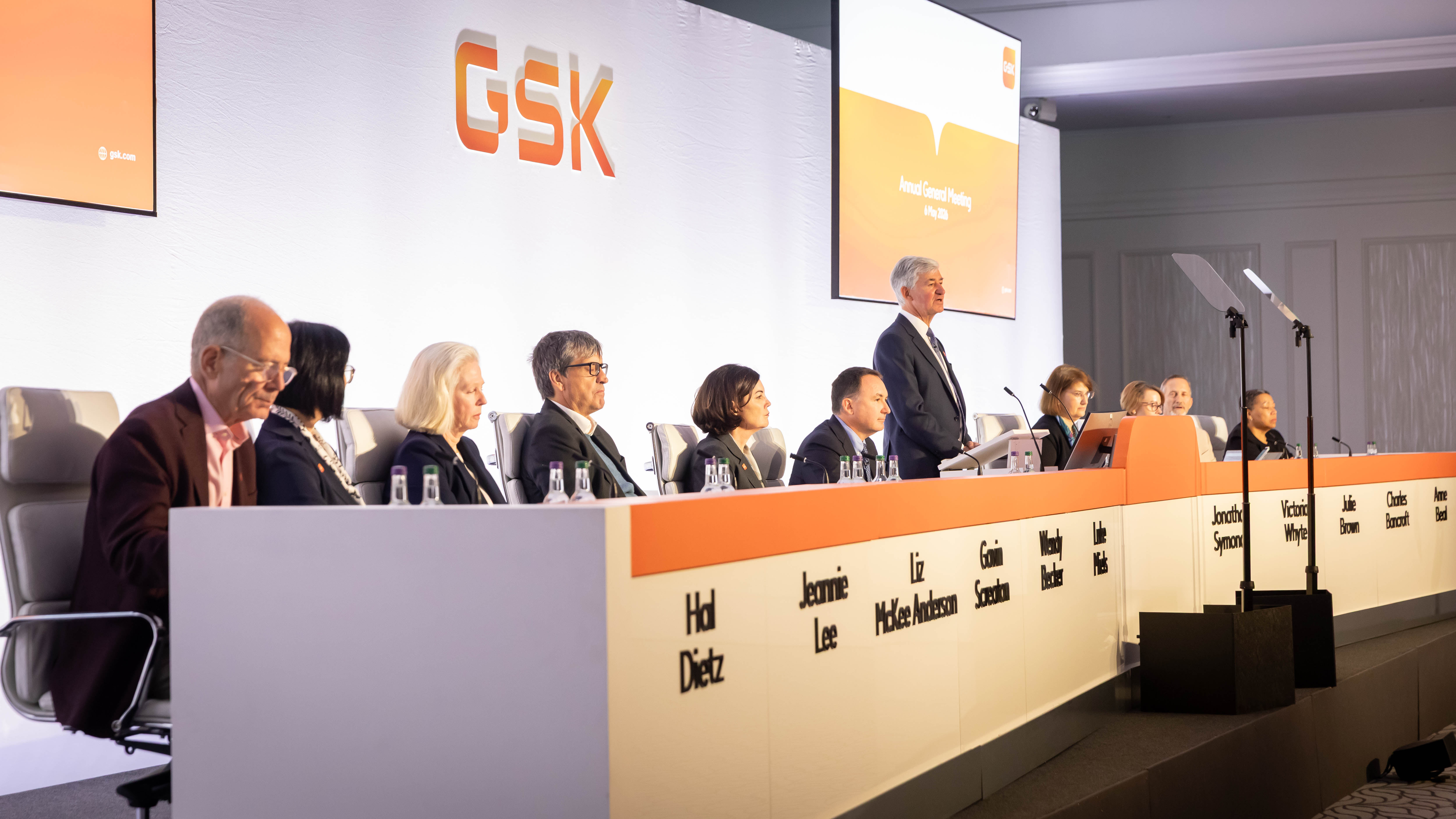 GSK Board on stage at AGM listen to Chair, Jon Symonds speaking