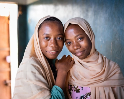 Two sisters in Zanzibar living with neglected tropical diseases looking at camera smiling