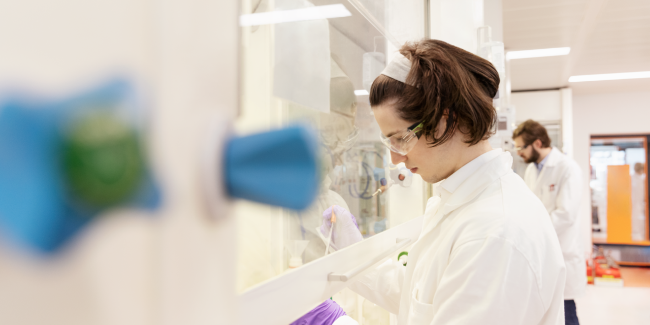 Scientist uses syringe behind plastic screen