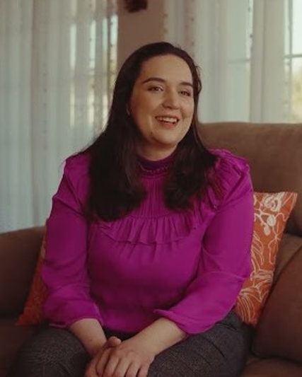 Angeles sitting on a sofa in a pink shirt