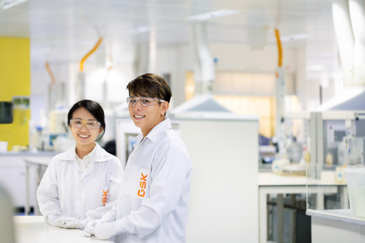 Two scientists in a lab looking at camera smiling
