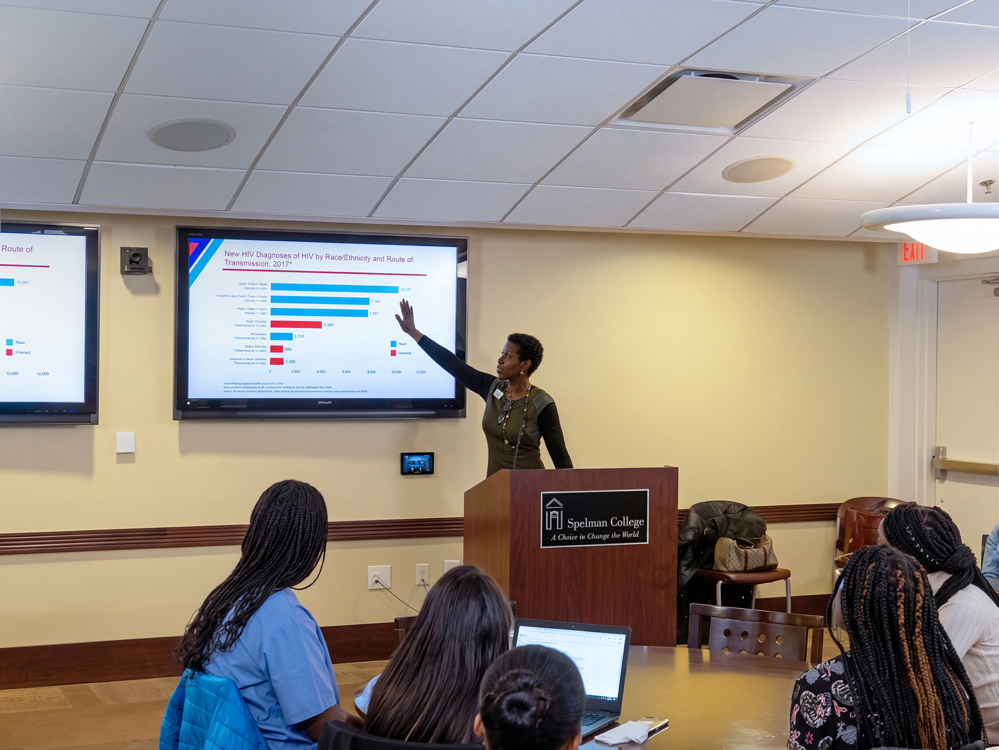 Zandraetta pointing to a projector, addressing a room of women