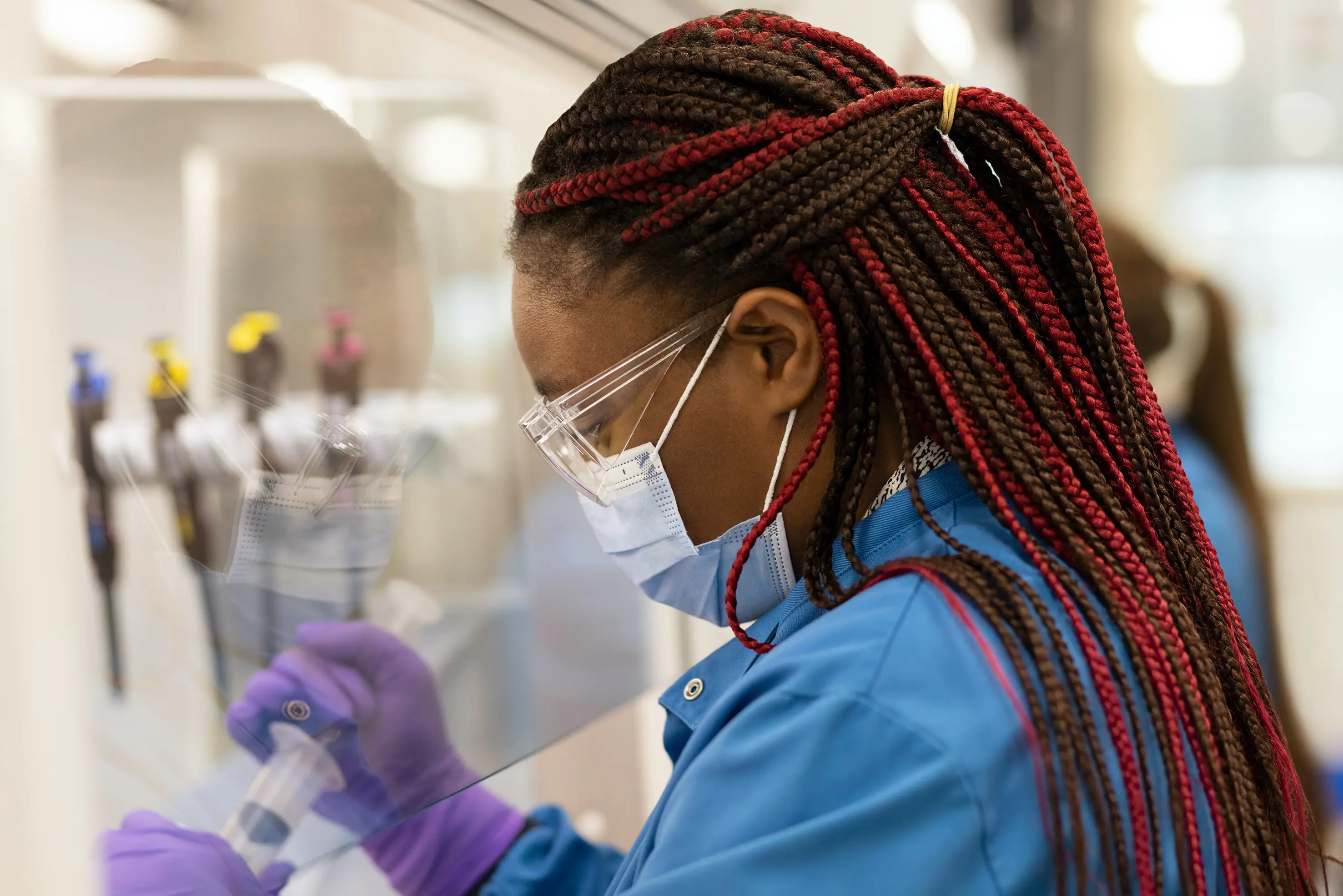 Scientist using syringe behind protective screen cover