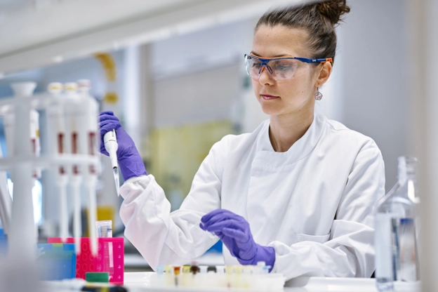 Woman in lab coat using a syringe