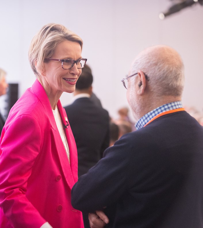 CEO Emma Walmsley, woman in pink suit, speaks to man at AGM