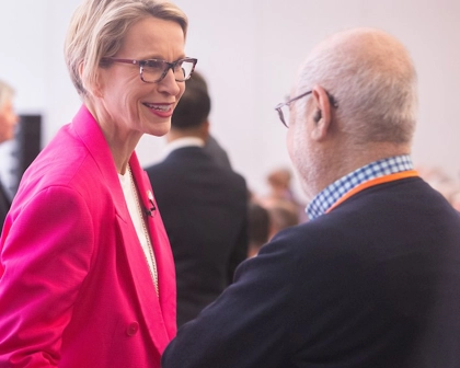 CEO Emma Walmsley, woman in pink suit, speaks to man at AGM