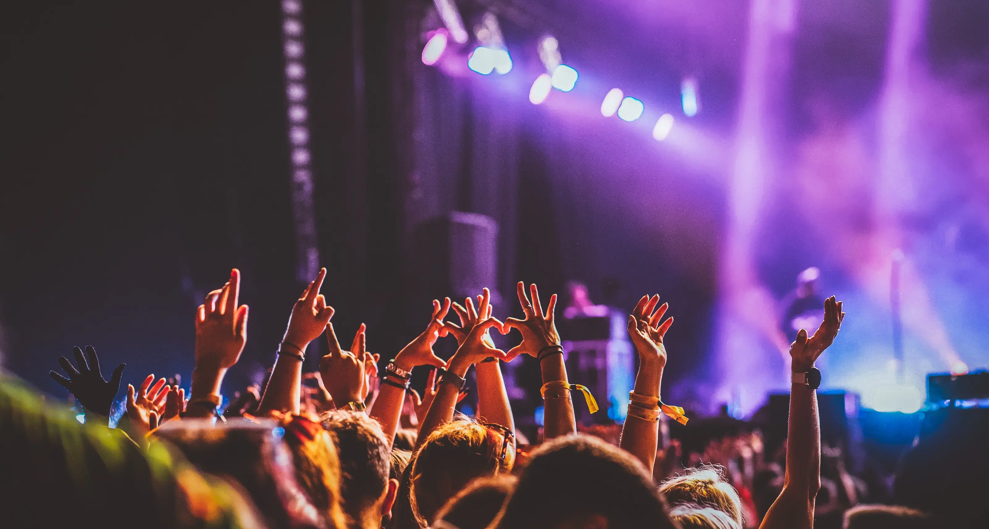 Young people with hands in the air in front of a festival stage