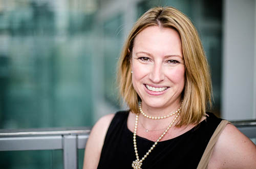 Woman in black top and pearl necklace smiles
