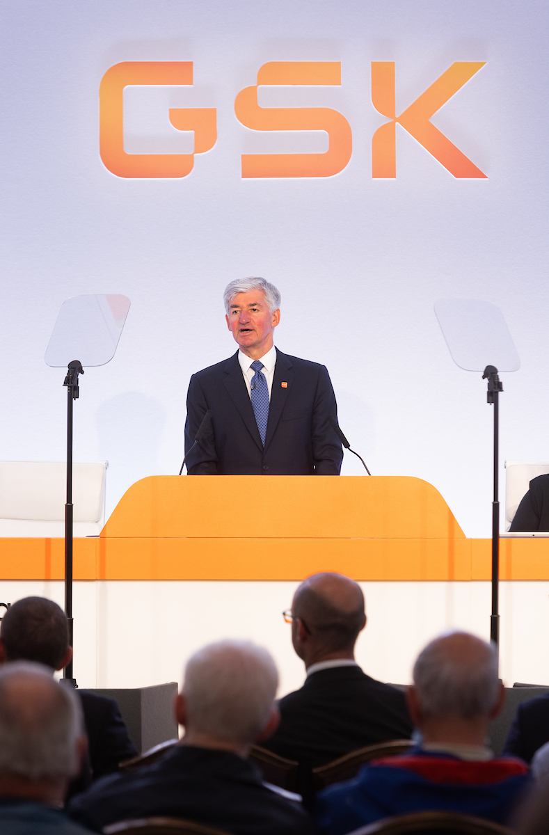 GSK Chair, Jon Symonds speaks, at podium on stage, at 2024 AGM