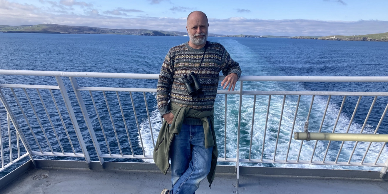 Patient stands on balcony in front of lake