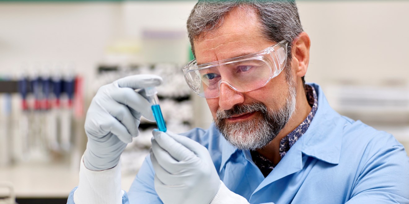Lab worker examining a blue vial