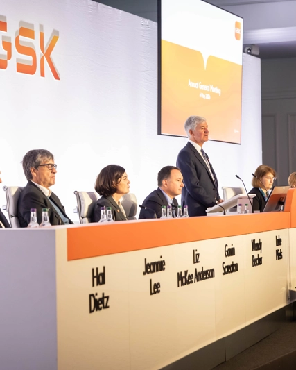 GSK Board on stage at AGM listen to Chair, Jon Symonds speaking