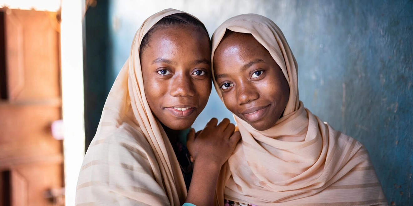 Two sisters in Zanzibar living with neglected tropical diseases looking at camera smiling