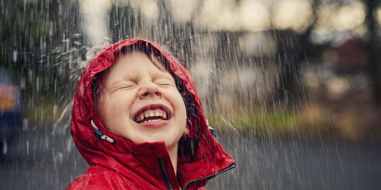 Happy smiling boy stood outdoors in the rain