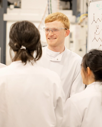 R&D scientist discussing chemistry formulas and collaborating with team.