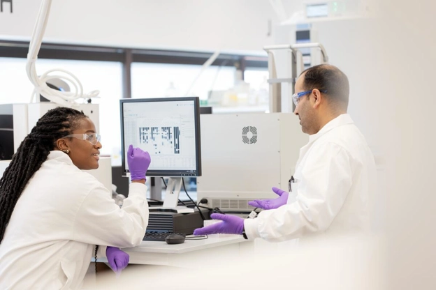 Two scientists collaborating at a computer desk in lab
