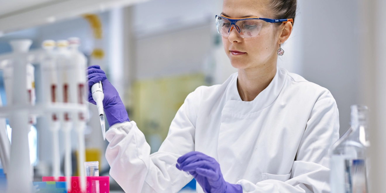 Woman in lab coat using a syringe