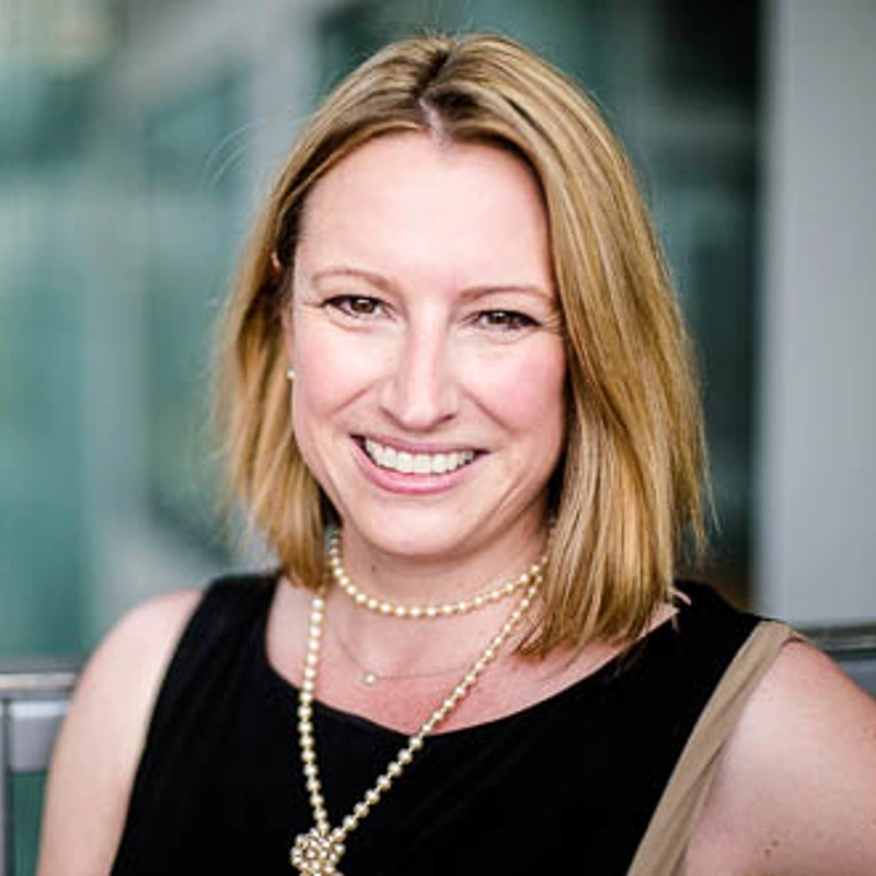 Woman in black top and pearl necklace smiles