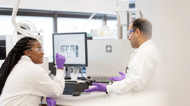 two scientists collaborating at computer in lab