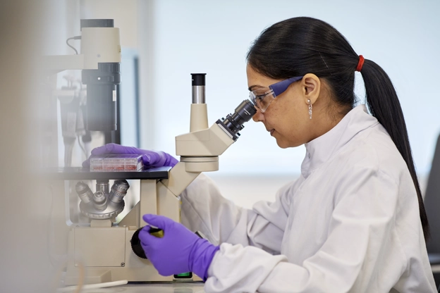 Cellular and molecular biologist looking into microscope